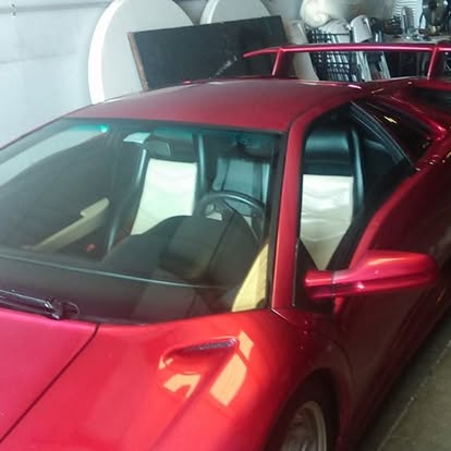 Red sedan with open driver door in indoor parking garage