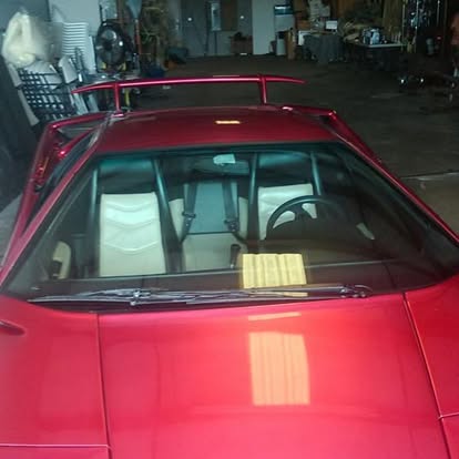 Red vintage car with roof rack displayed in indoor showroom
