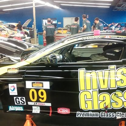Black racing car with yellow graphics at indoor automotive event