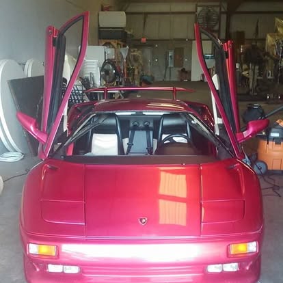 Red sports car with open gull-wing doors in garage showroom