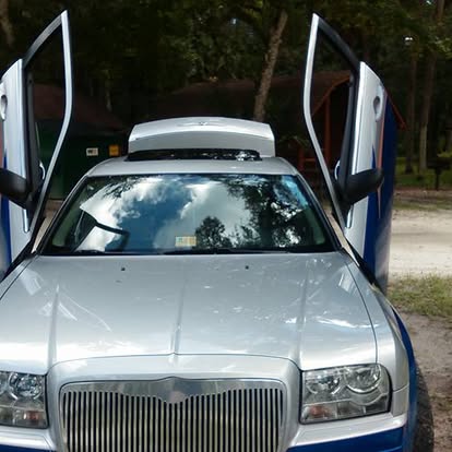Silver luxury sedan with open gull-wing doors parked outdoors