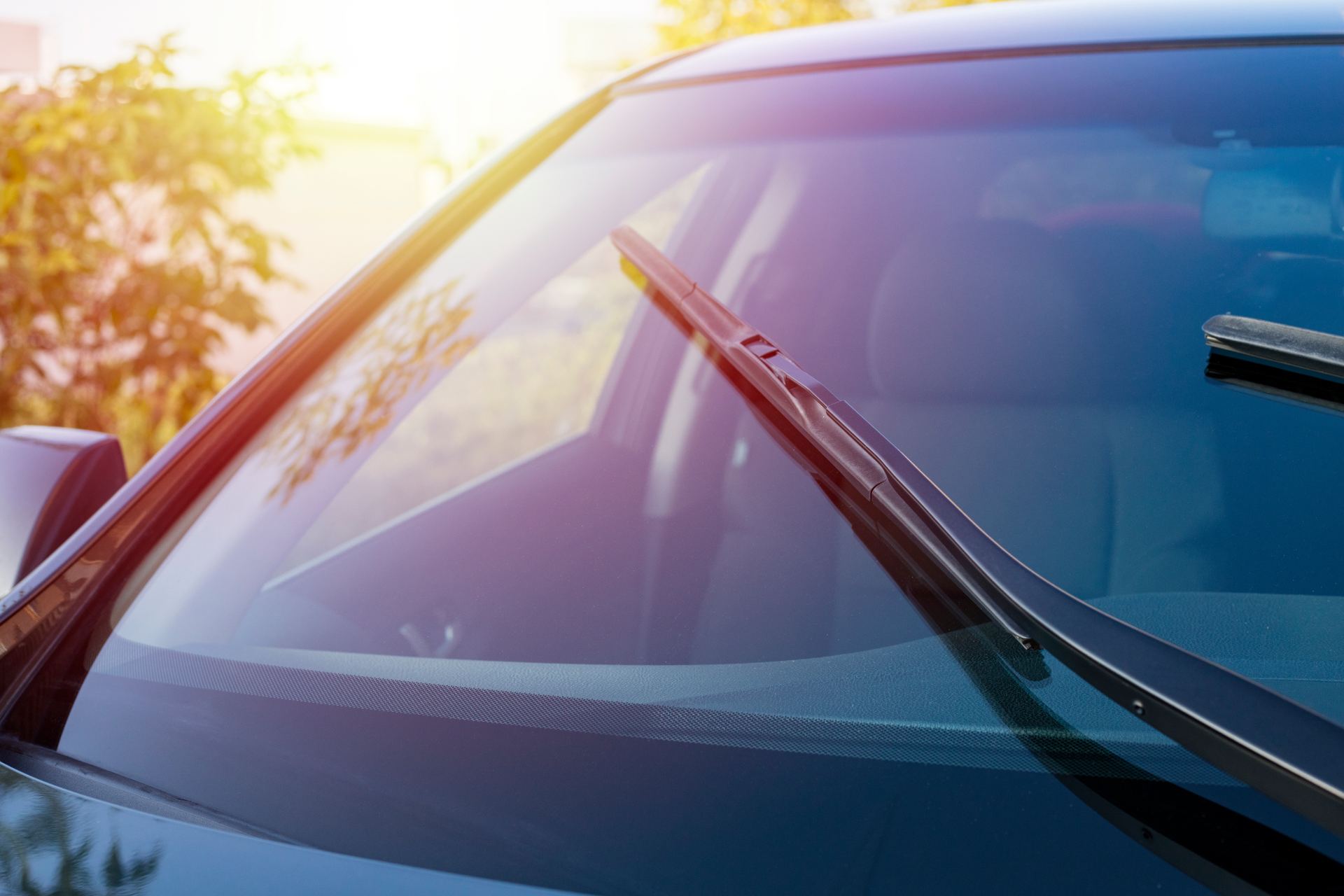 Car windshield with wipers during sunny afternoon light