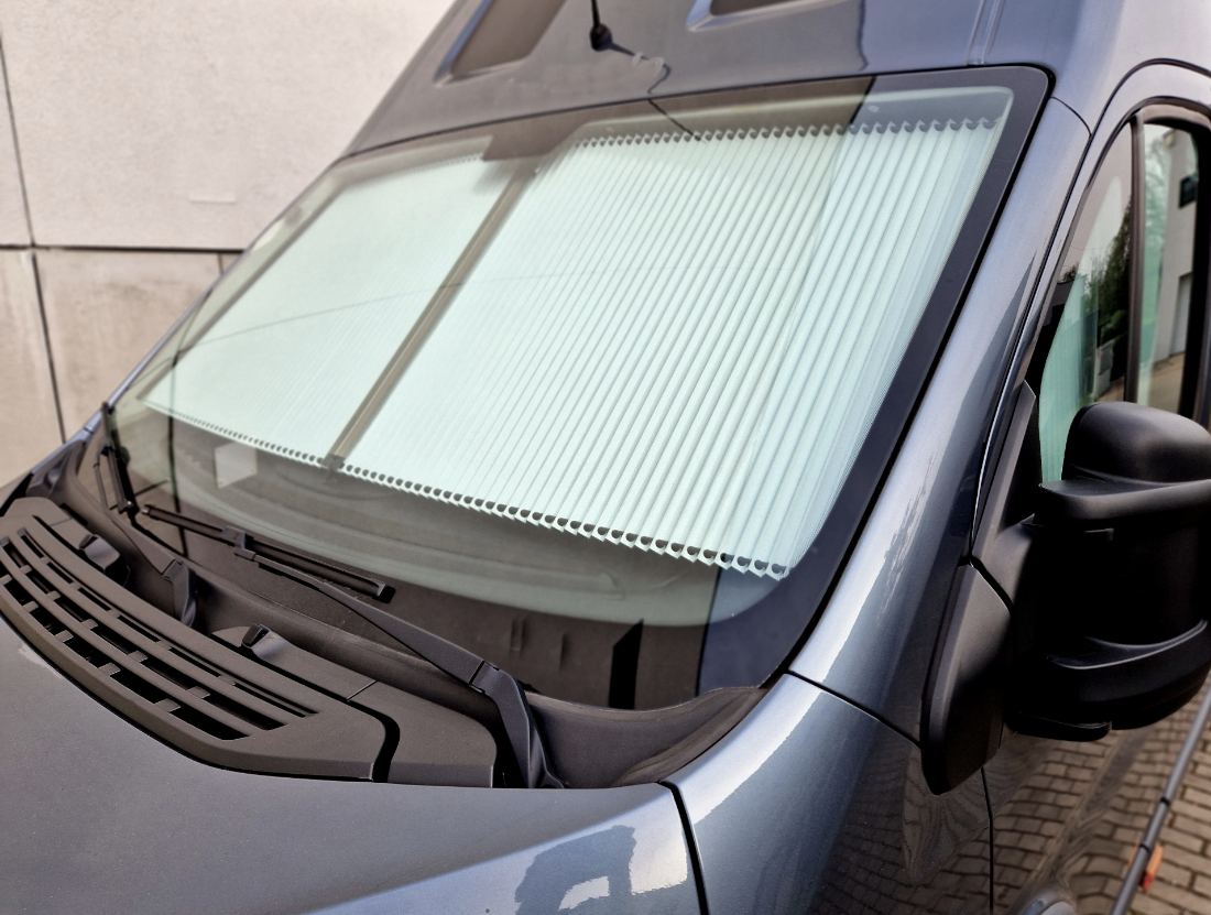 Silver van with white accordion-style sun shade covering the windshield