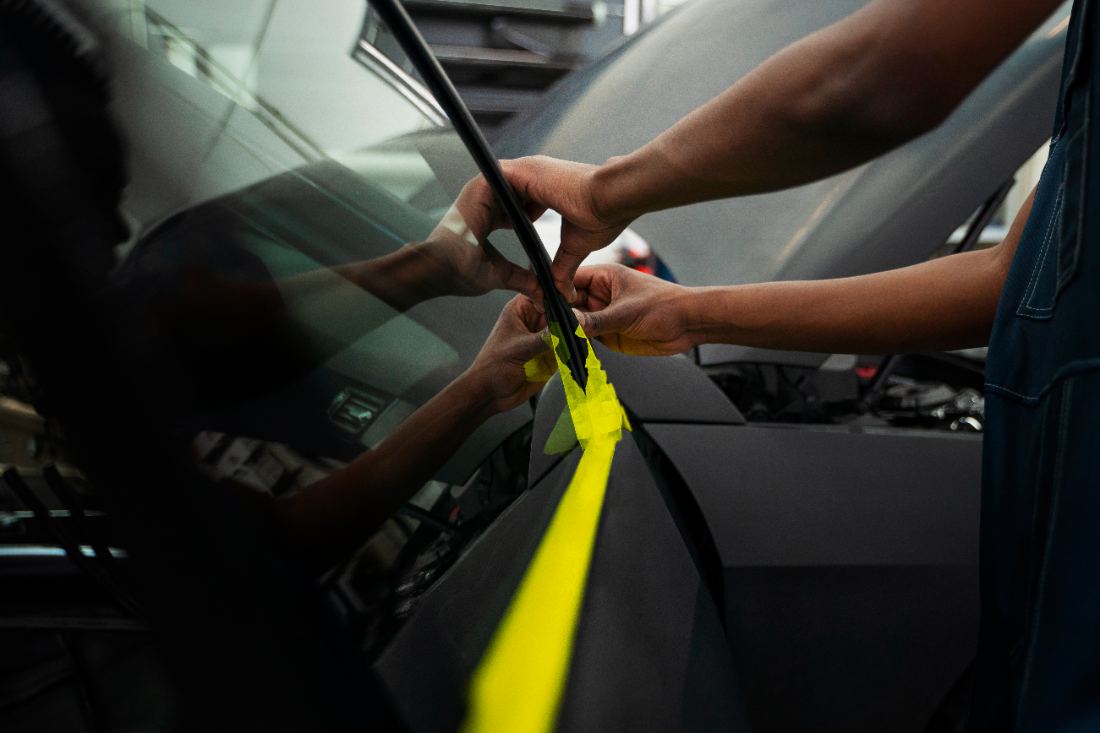 Two people applying yellow safety tape to a car door interior
